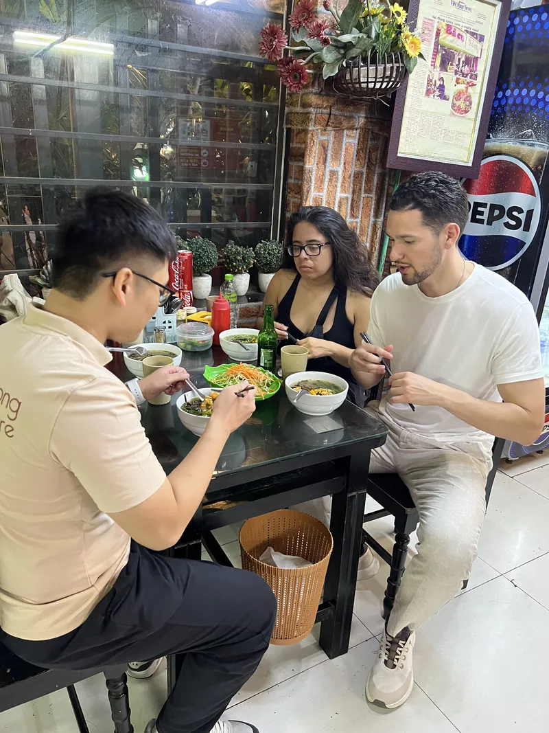 Guide and foreign couple eating banh da cua, Haiphong's famous crab noodle soup