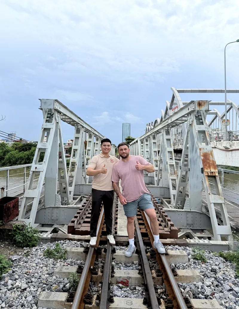 Two travelers posing on the tracks of Cau Quay, Haiphong's historic swing bridge