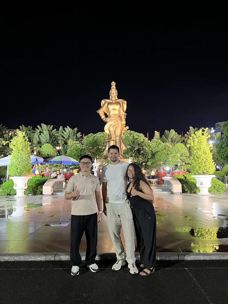 Free Things To Do In Haiphong For Budget Travel 2 Local guide with a foreign couple at the golden Le Chan statue square in Haiphong at night