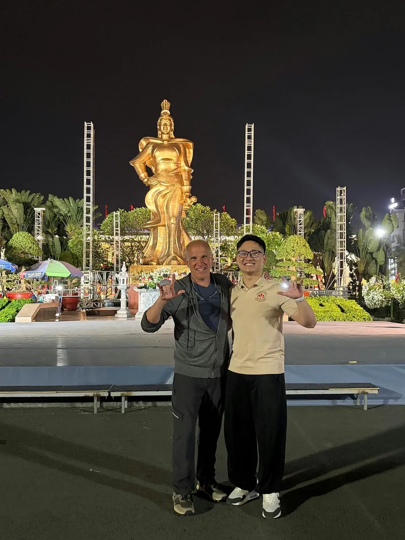 Traveler and guide at the golden Le Chan statue square in Haiphong at night
