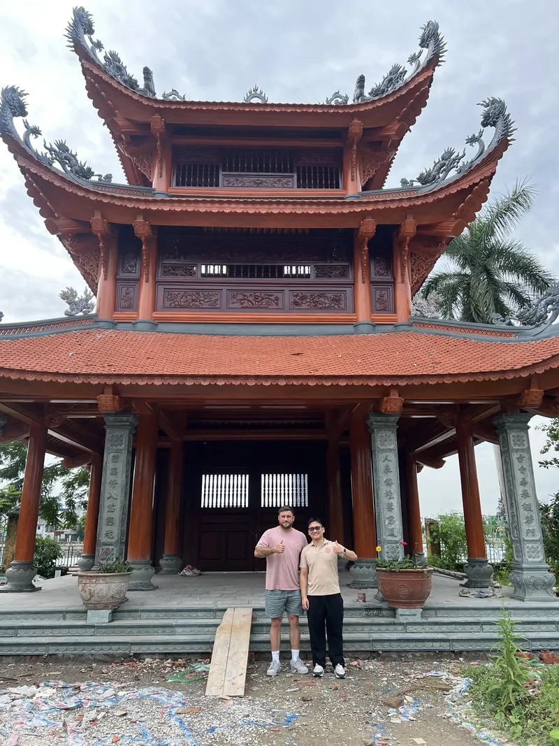 Guide and traveler in front of the red-roofed bell tower of Linh Quang Pagoda in Haiphong