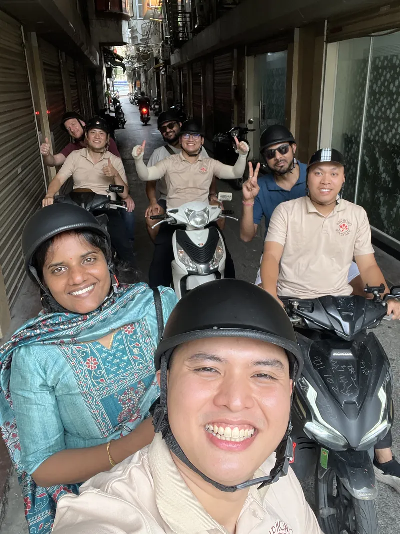Selfie of a smiling guide with travelers on motorbikes in a local residential alley in Haiphong