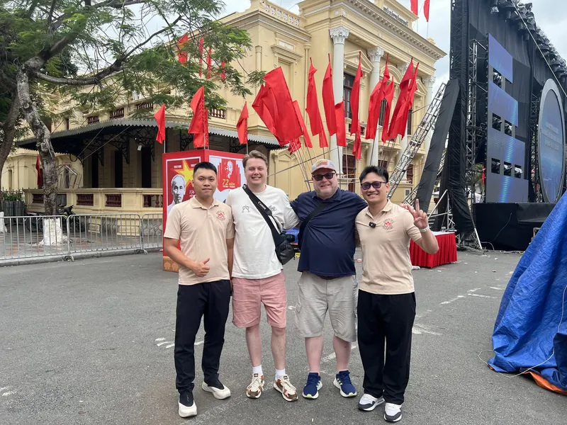 Guides and travelers by Haiphong Opera House decorated with red flags