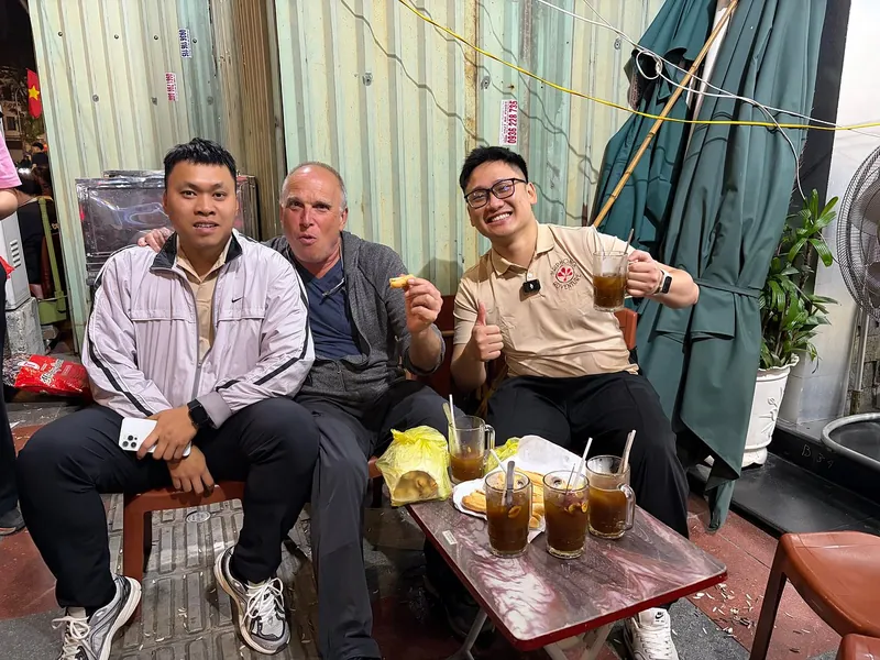 Guides and a foreign traveler enjoying Vietnamese iced coffee at a Haiphong sidewalk cafe